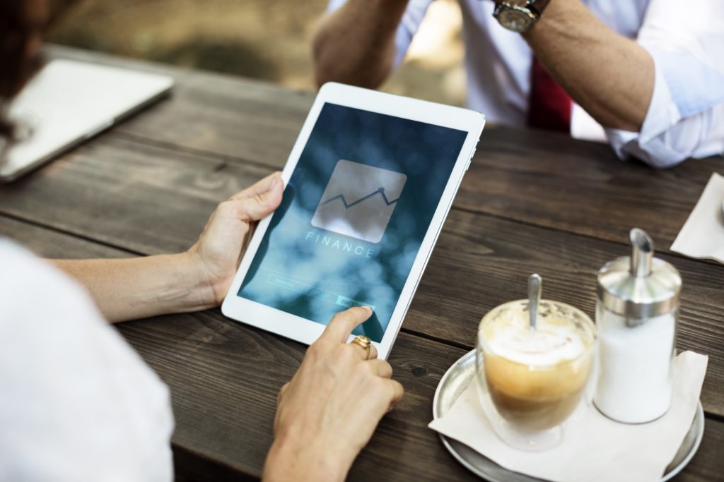 personne consultant des chiffres financiers sur une tablette, à une table