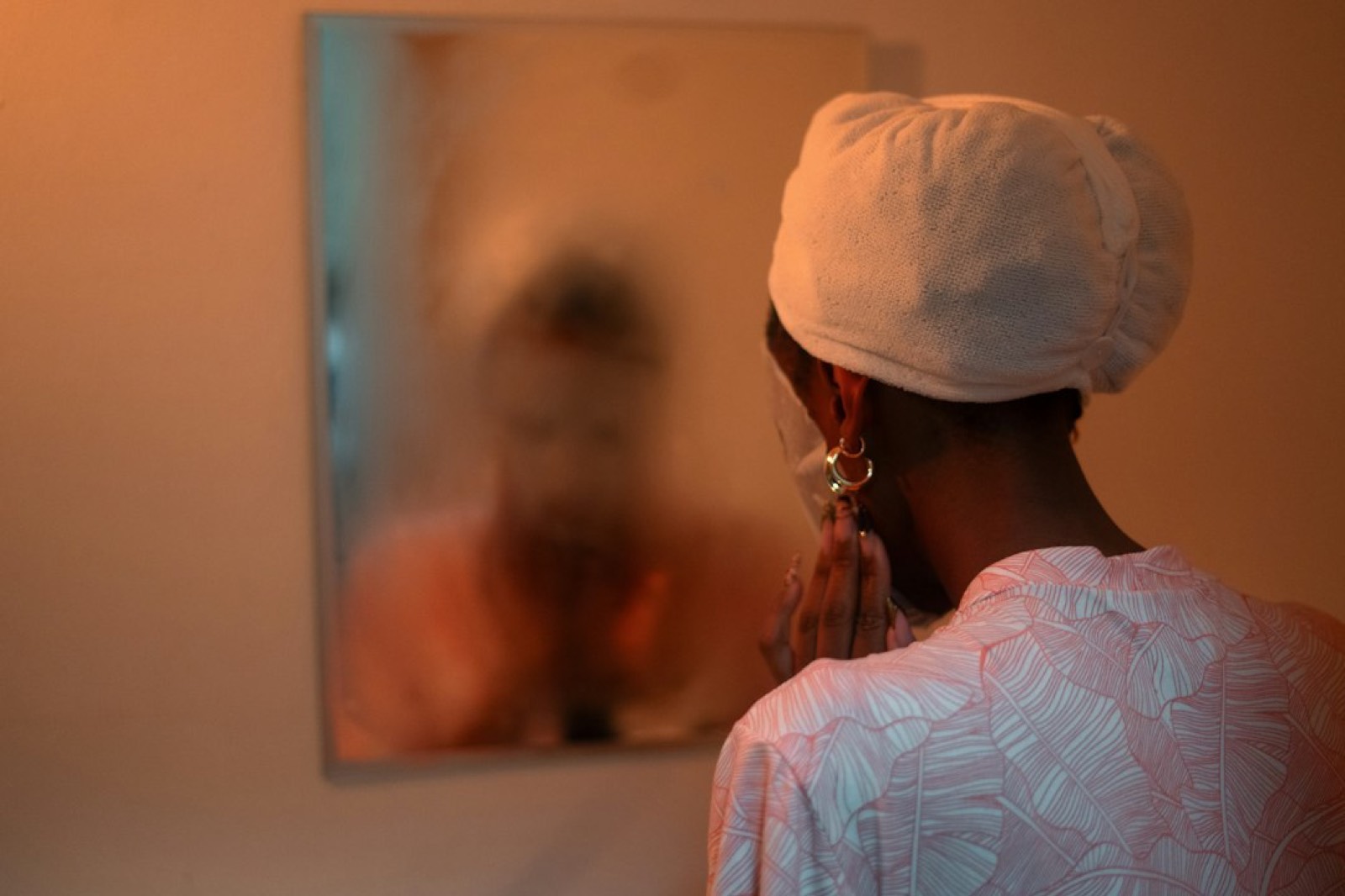 Femme nouant un foulard en satin devant un miroir avant de dormir